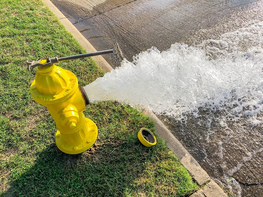 top-view-yellow-fire-hydrant-gushing-water-across-a-residential