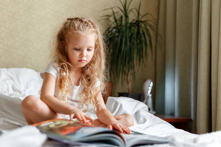 beautiful-little-child-calm-attentive-child-read-book-on-bed-li