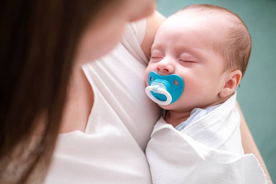 little-newborn-baby-boy-sleeping-with-baby-dummy-on-mother-hands