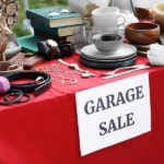 paper-with-sign-garage-sale-and-many-different-items-on-red-tabl