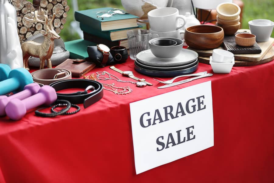 paper-with-sign-garage-sale-and-many-different-items-on-red-tabl
