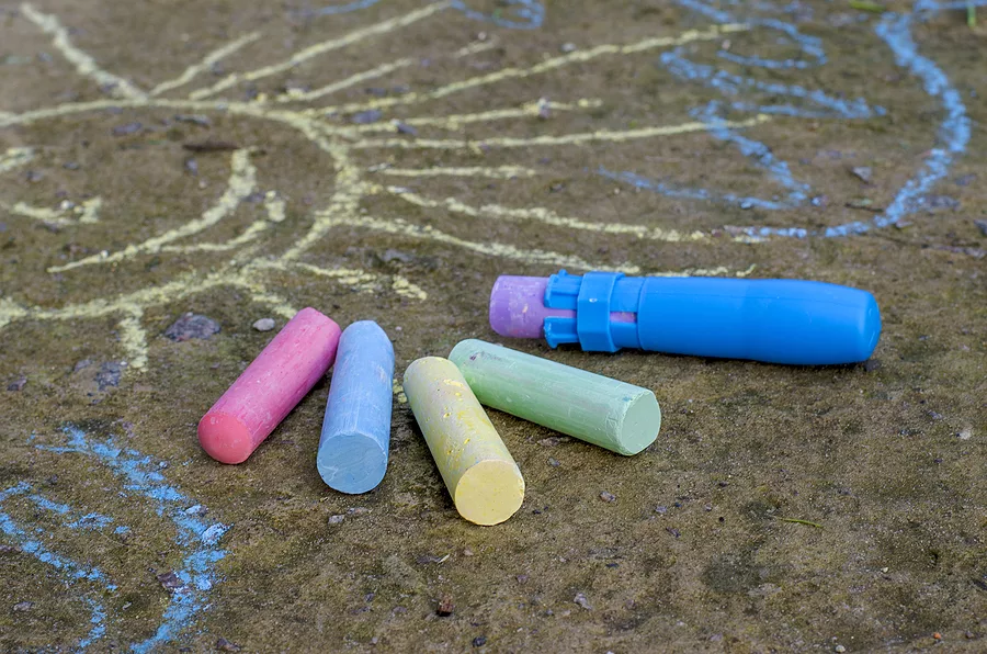 childrens-multi-colored-chalk-and-chalk-holder-on-the-asphalt