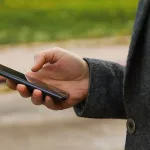 defocus-male-hand-holding-phone-man-using-smart-phone-in-autumn