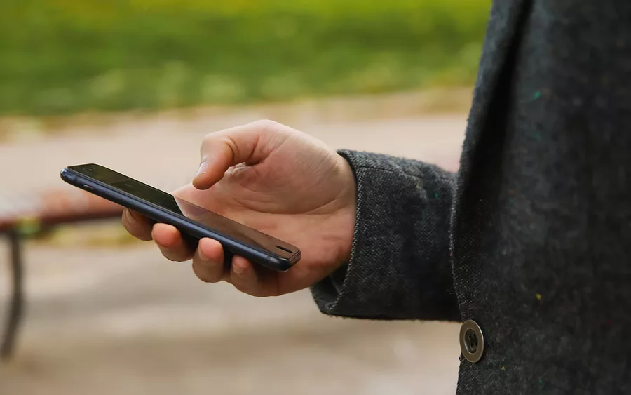 defocus-male-hand-holding-phone-man-using-smart-phone-in-autumn