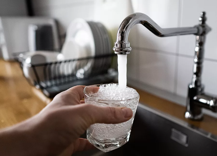 man-filling-a-glass-of-water-from-a-stainless-steel-kitchen-tap