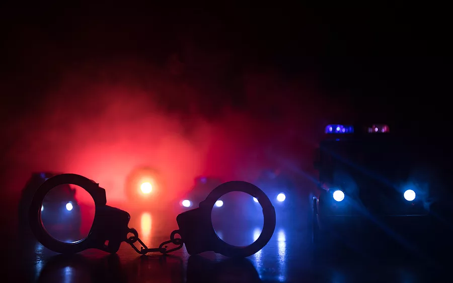closed-handcuffs-on-the-street-pavement-at-night-with-police-car