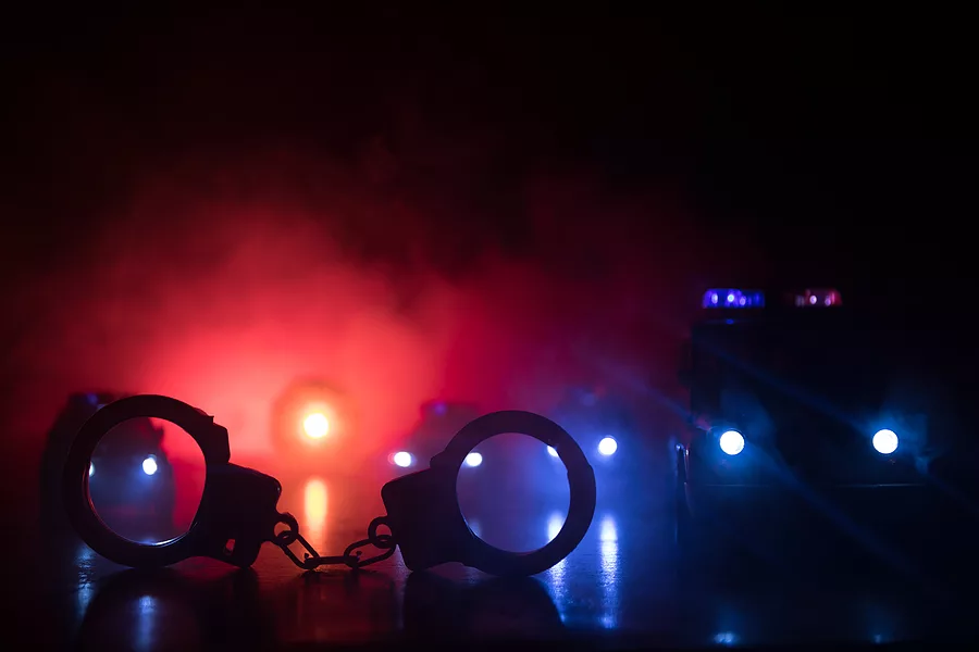 closed-handcuffs-on-the-street-pavement-at-night-with-police-car