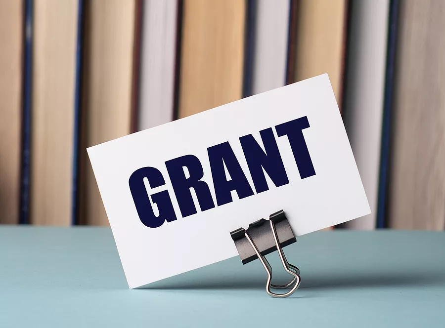a-white-card-with-the-text-grant-stands-on-a-clip-for-papers-on