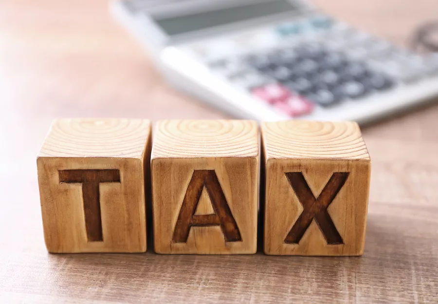 wooden-cubes-with-word-tax-and-calculator-on-background