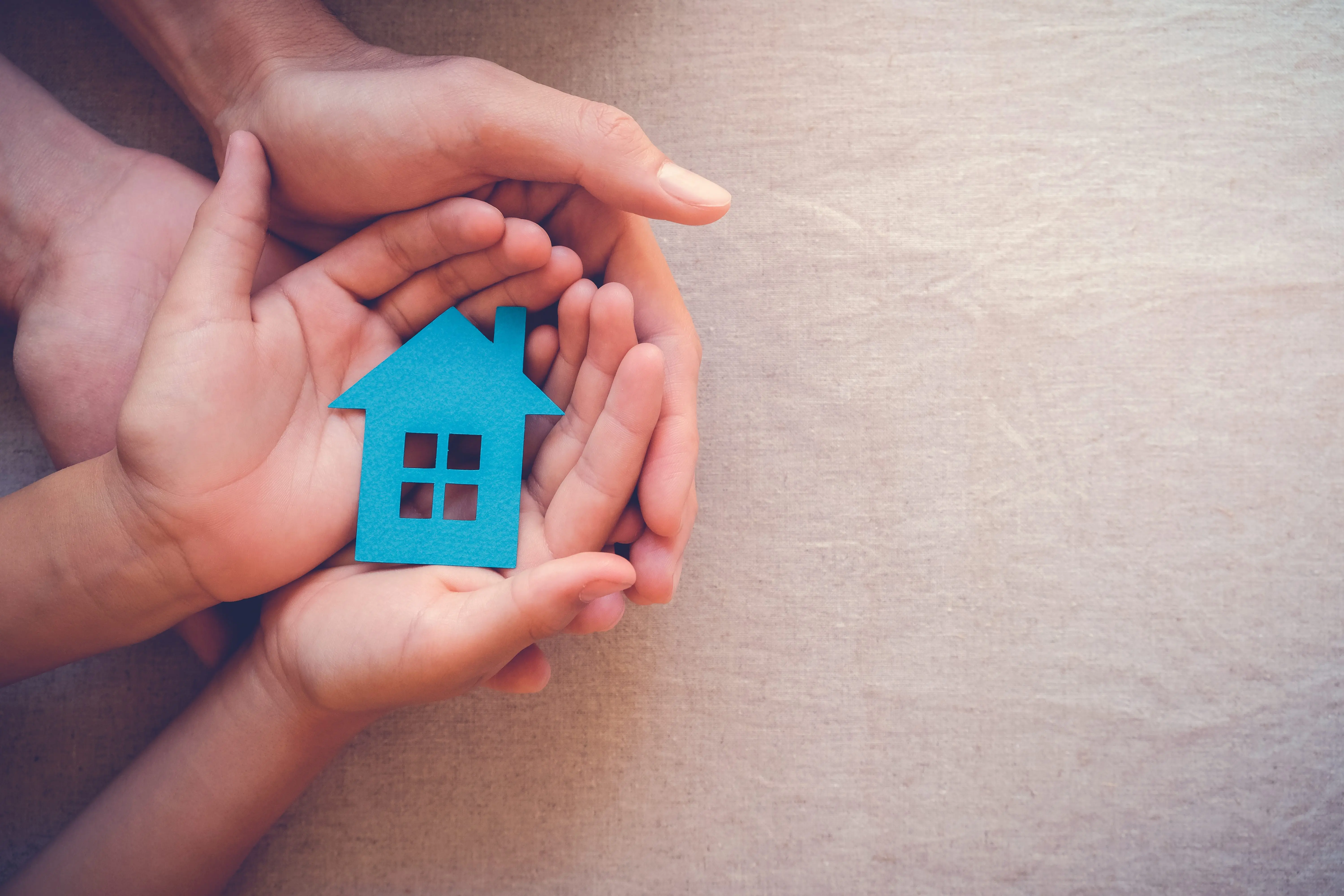 hands-holding-paper-house-family-home-homeless-shelter-international-day-of-families-foster-home-care-family-day-care-mortgage-housing-crisis-concept