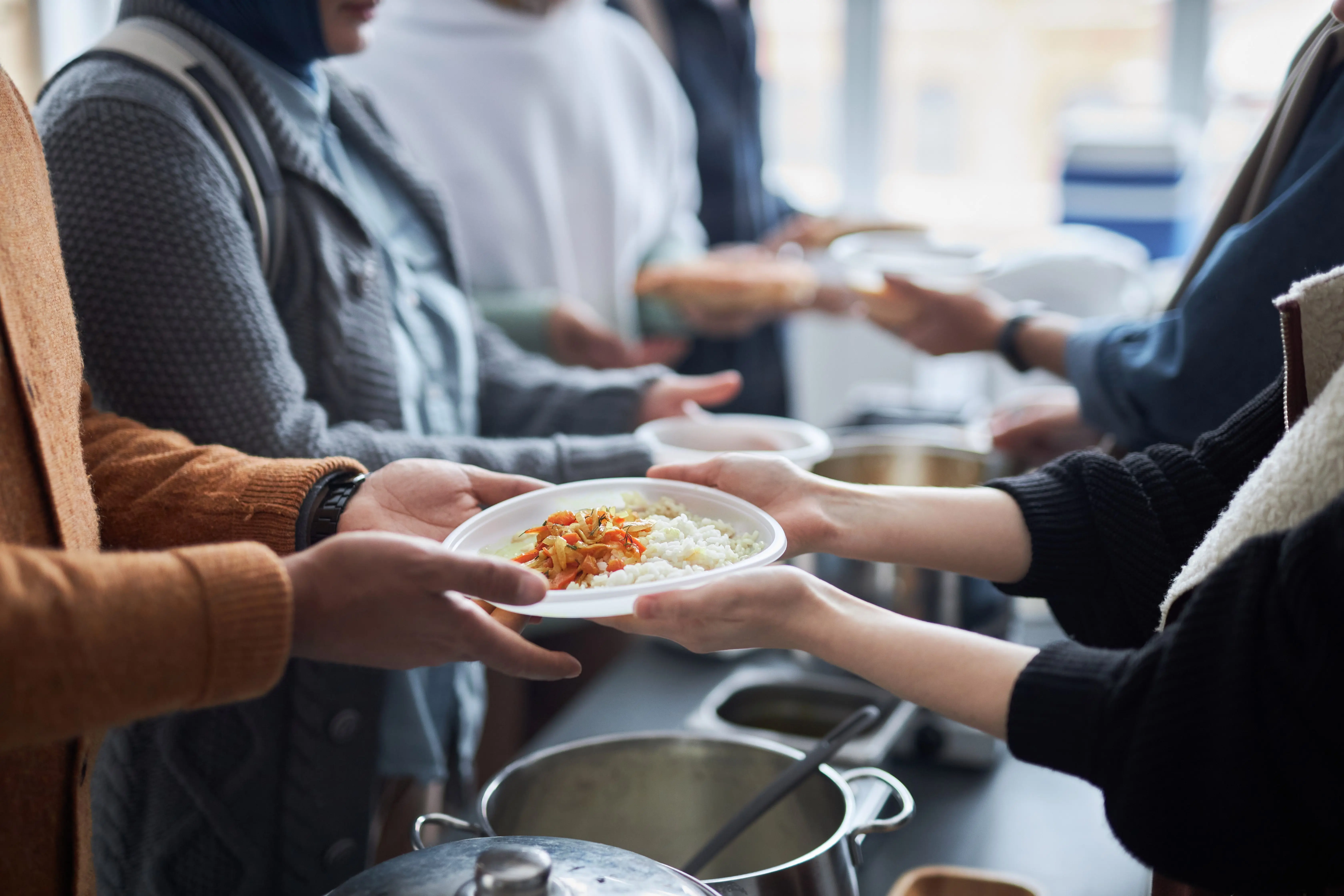 volunteer-giving-meals-to-refugees-standing-in-line