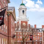 View of the architecture of the famous Harvard University in Cambridge^ Massachusetts^ USA showcasing it brick buildings with some students and locals passing by . Cambridge^ MA^ USA - March 15^ 2024