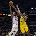 Realistic photography of two basketball players fighting in the air to catch the ball falling after a failed shot in an nba game. one basketball player is from the oklahoma city thunder and the other basketball player is from the indiana pacers. the photo
