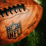 NFL background photo. Ball placed on green grass in beautiful light. NEW YORK^ USA^ SEPTEMBER 11^ 2023