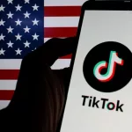 Photo illustration of TikTok logo displayed on a smartphone with American Flag in the background.