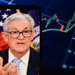 On the smartphone screen^ Federal Reserve (Fed) Chair Jerome Powell is visible. In the background^ an inflation rate chart is displayed. 19.04.2025. New York^ U.S