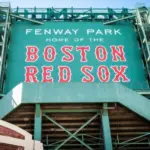 View of the historic architecture of the Fenway Park Stadium showcasing its signs^ brick walls^ statues^ and the famous green color and red letters of the red sox. Boston^ MA^ USA - March 10^ 2023