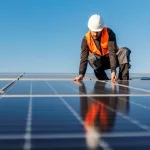 A worker installing solar panels on the roof