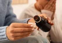 Mother giving cough syrup to her sick son in bed