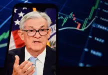 Federal Reserve (Fed) Chair Jerome Powell is visible. In the background^ an inflation rate chart is displayed.