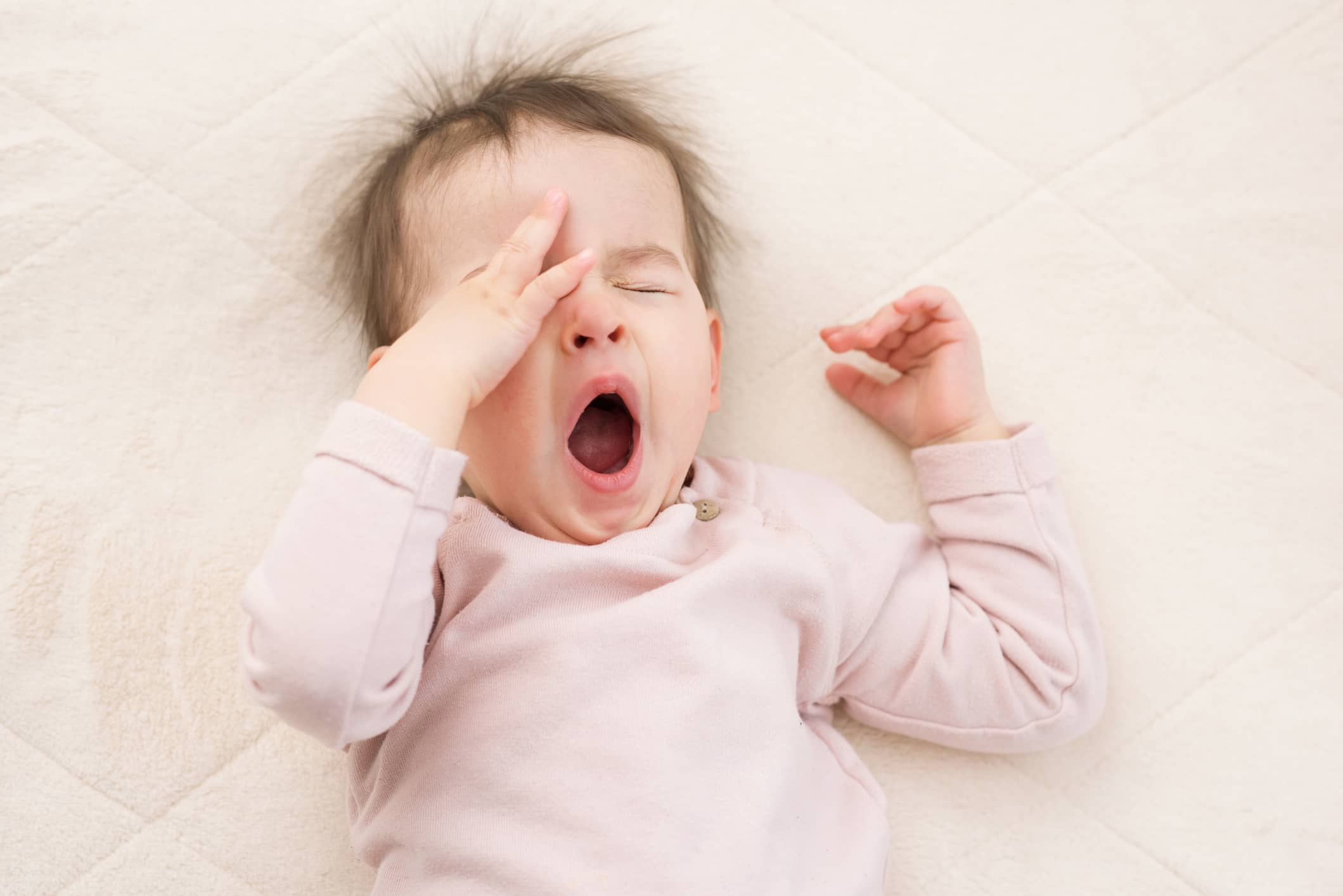 portrait-of-sleeping-beautiful-and-yawning-baby-toddler-on-the-bed-wearing-pink-pullover-bedtime-nursery