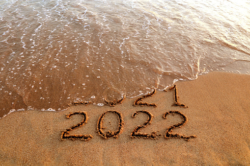 new-year-2022-and-old-year-2021-on-sandy-beach-with-waves