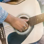 Close up woman's hands playing acoustic guitar.