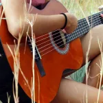 female country artist playing guitar outdoors