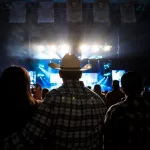 A country music fan watches a live concert wearing a cowboy hat.