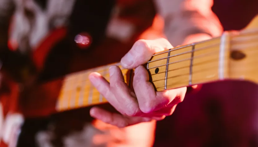 Close up look of hands of a man playing the electric guitar during a concert