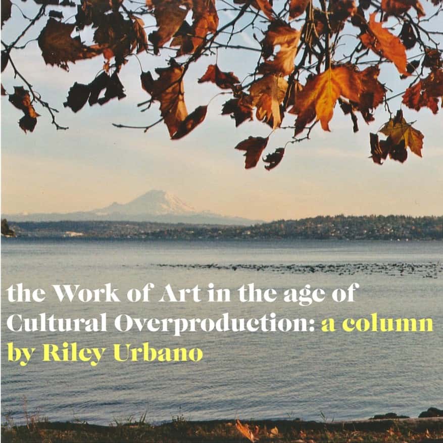 Photo of lake with a mountain in the background and autumn leaves in the foreground. Over the photo some text reads "the work of art in the age of cultural overproduction:a column by Riley Urbano"