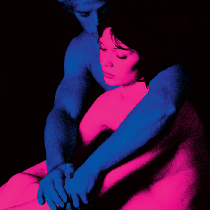A woman bathed in red light is embraced by a man bathed in blue light