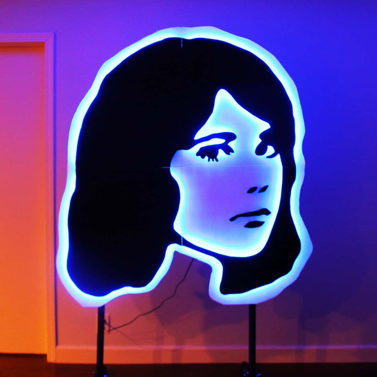 Neon outline of a woman's face on a red, blue, and purple background