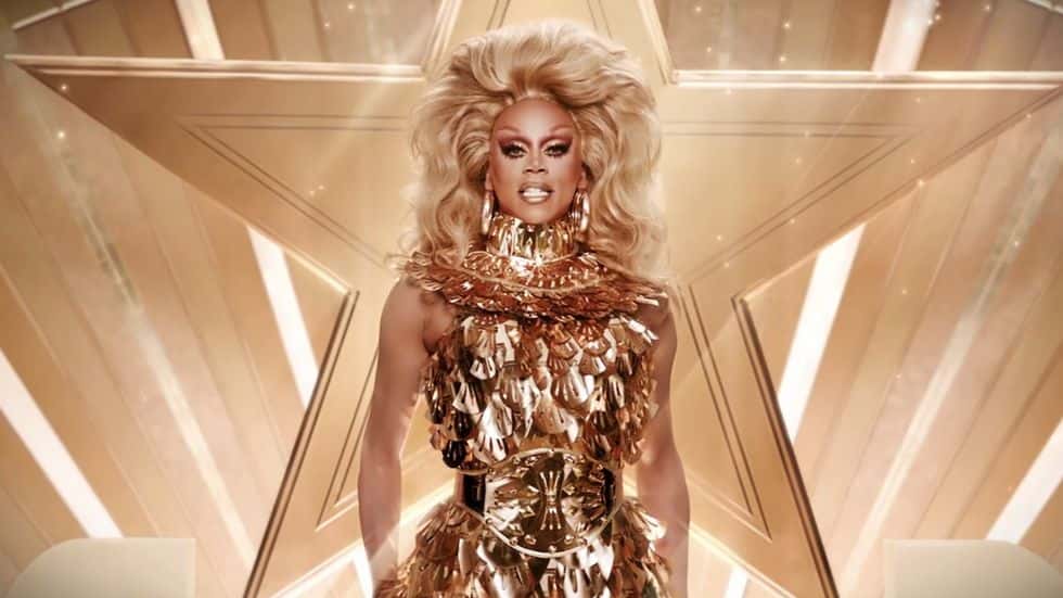RuPaul in drag on stage wearing all gold
