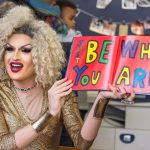 Toronto-based drag queen Erin B. holding open a copy of Be Who You Are by Todd Parr.