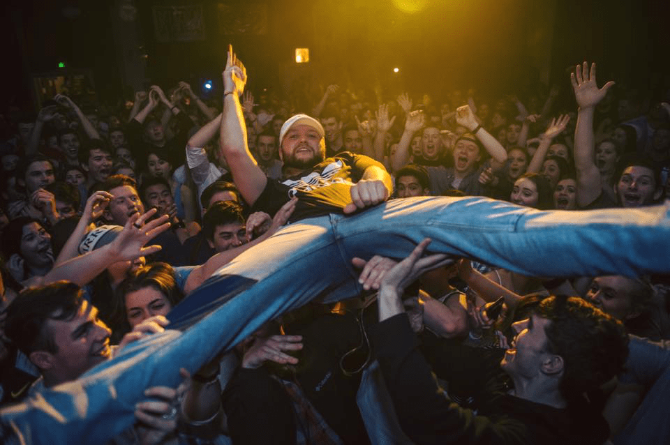 Quinn XCII diving into a crowd of fans (people, not windblowing). 