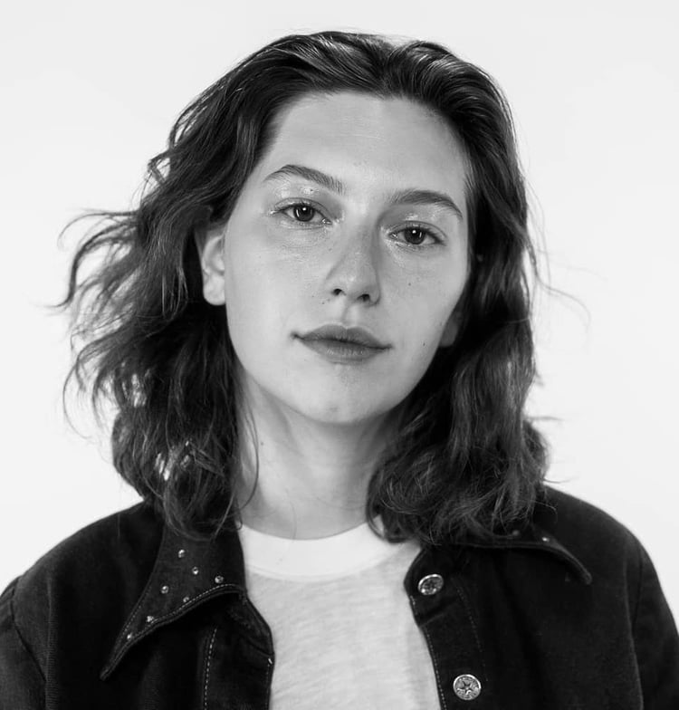 Black and white photo of King Princess. She stares directly at the camera with a slight grin on her face, almost like the Mona Lisa