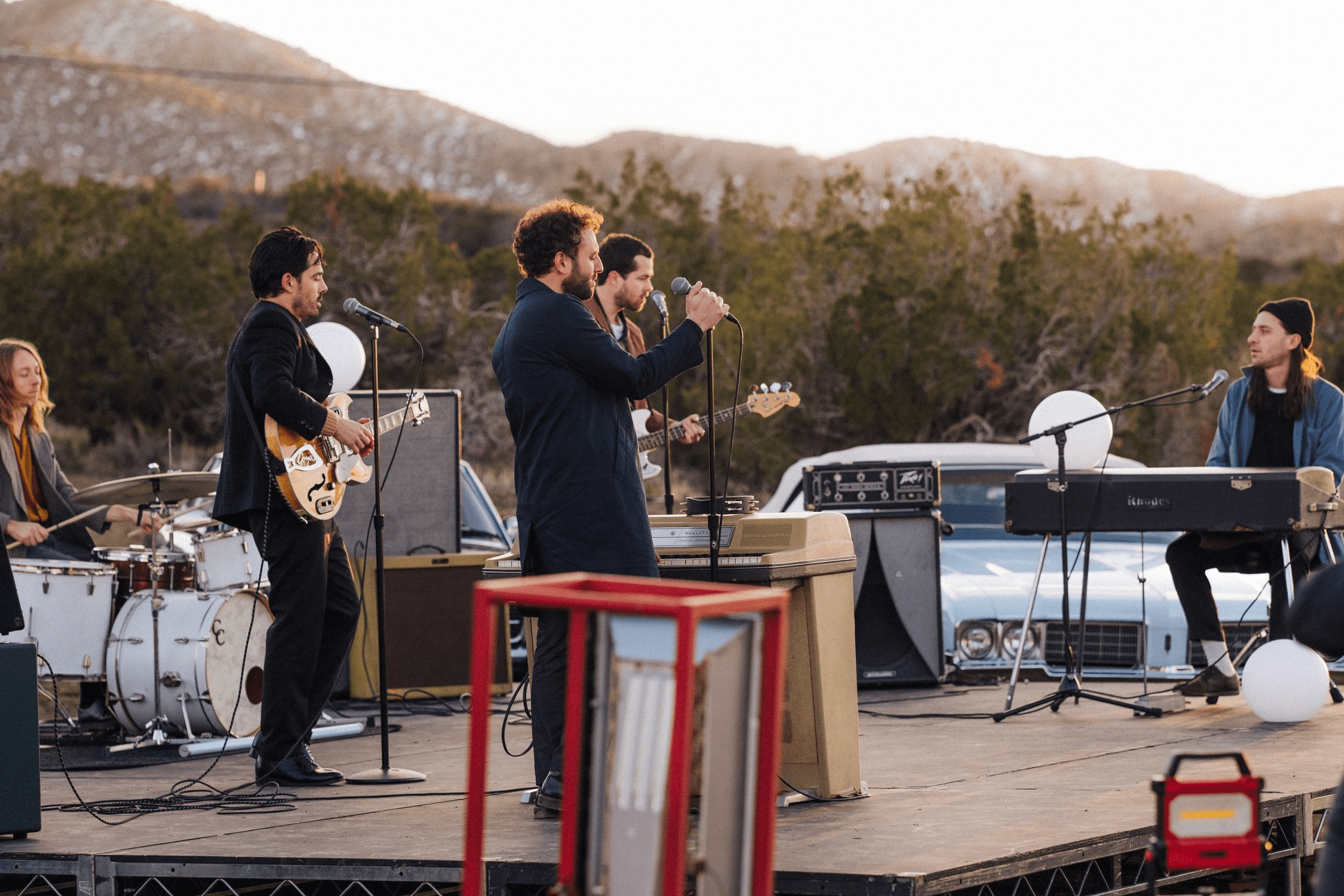 The members of Local Natives preform on an outdoor stage in the desert