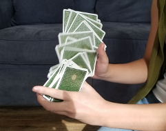 a deck of cards is shown in motion. They are falling from a person's right hand into their left.