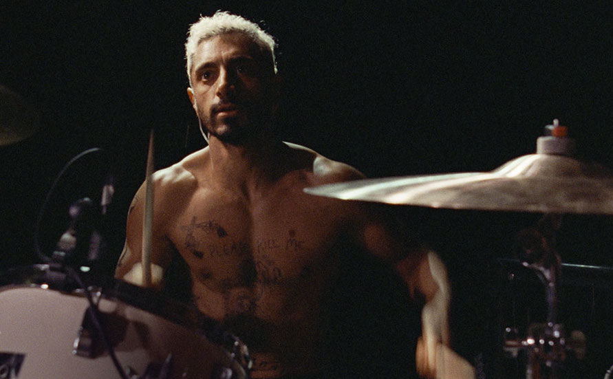 Riz Ahmed as Reuben in Sound of Metal sitting behind a drum set.