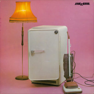 The Cure Album cover: It has an old fridge, a vacuum, and a tall lamp in front of a pink backdrop