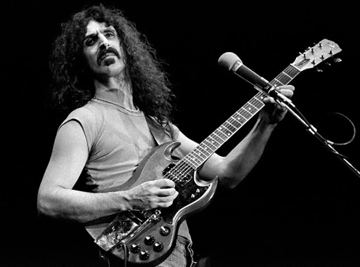 Black and white image of Frank Zappa playing guitar