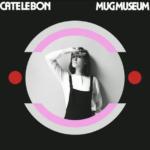 A black album cover with a black and white picture of Cate le Bon in overalls. The photo is cropped into a circle with a pink outline and two red dots on the left and right