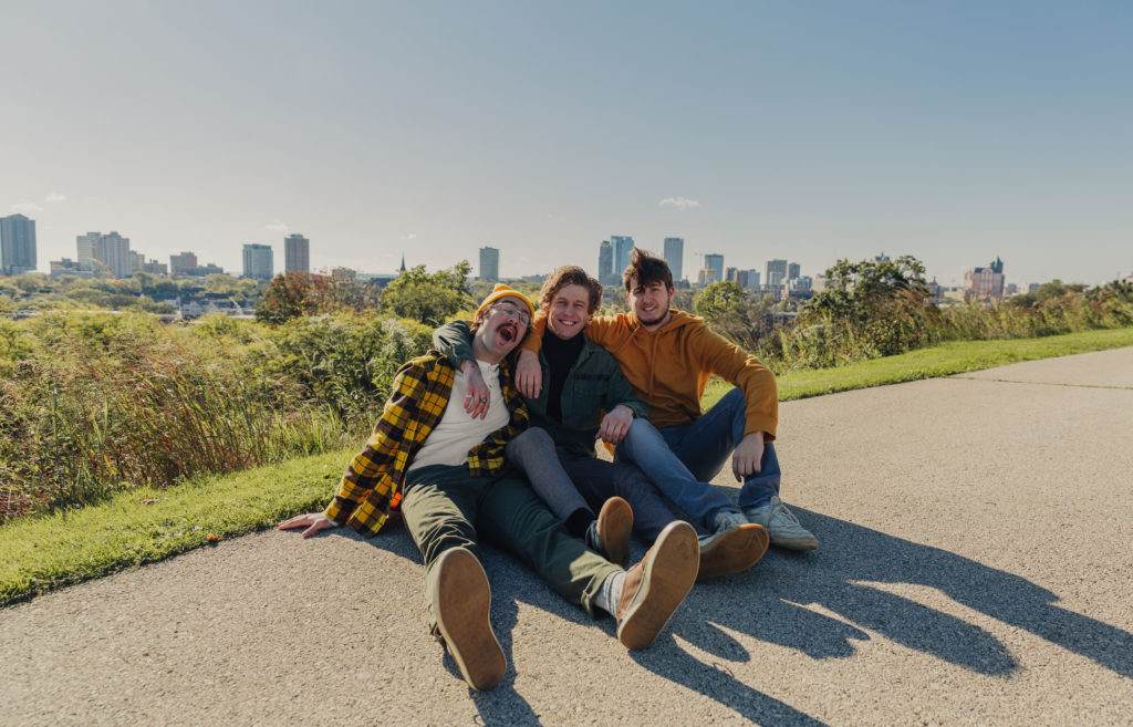 Band members of Diet Lite sit together with a city skyline behind them