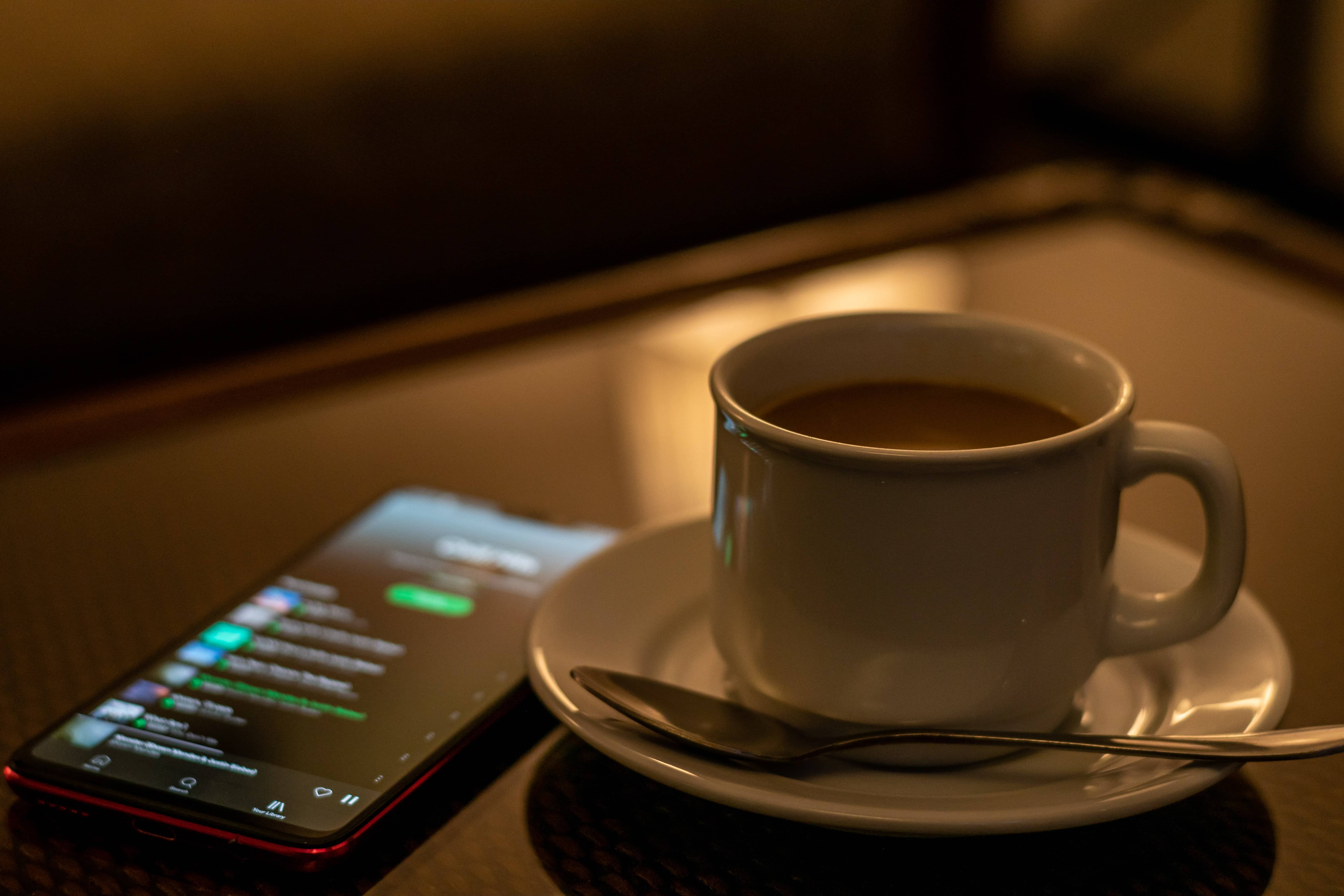 an iphone sitting next to a cup of coffee