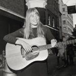joni mitchell young, holding a guitar