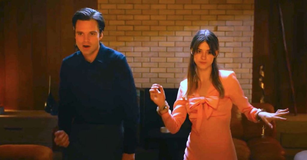 man with dark hair in a navy blue shirt dancing beside a woman with brown hair in a pink dress
