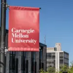 Carnegie Mellon University campus entrance sign with buildings in the background. Pittsburgh^ Pennsylvania^ USA- May 13^ 2021: Carnegie Mellon University campus entrance sign with buildings in the background. CMU is a private research university