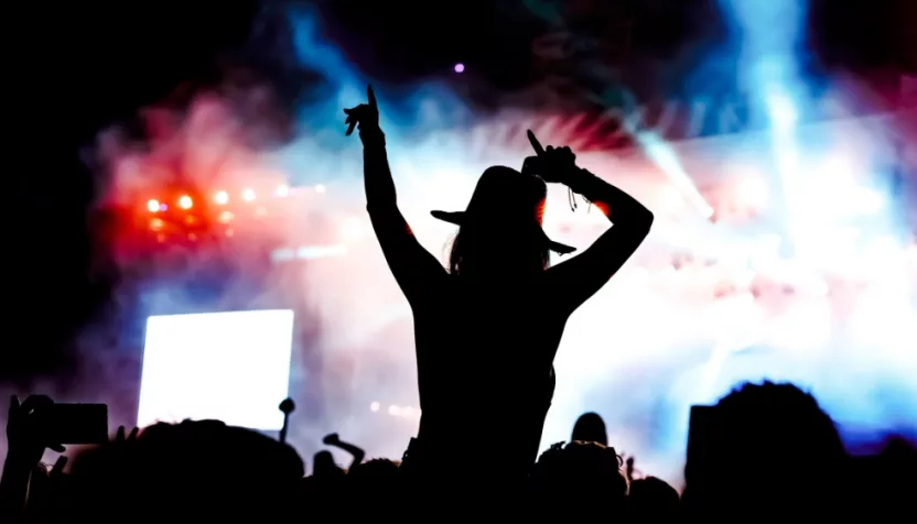 femela concertgoer in silhouette in front of stage lights^ watching show