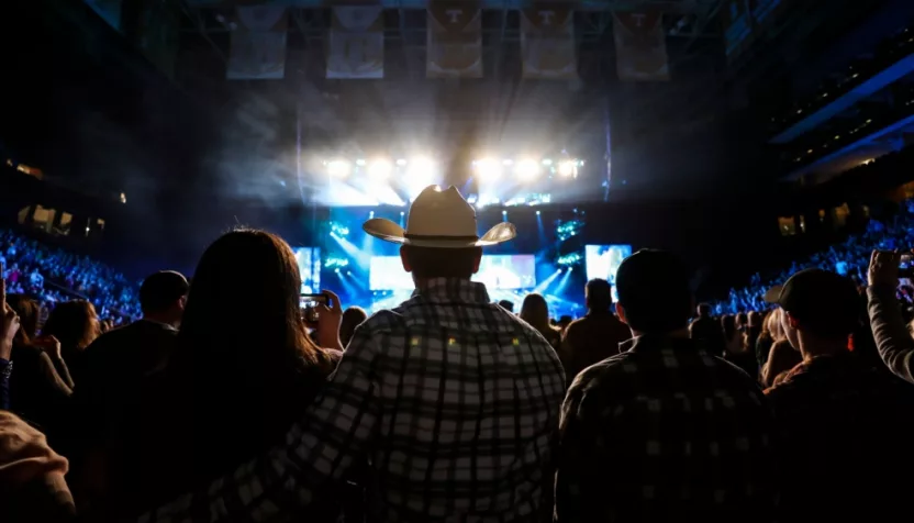 A country music fan watches a live concert wearing a cowboy hat.